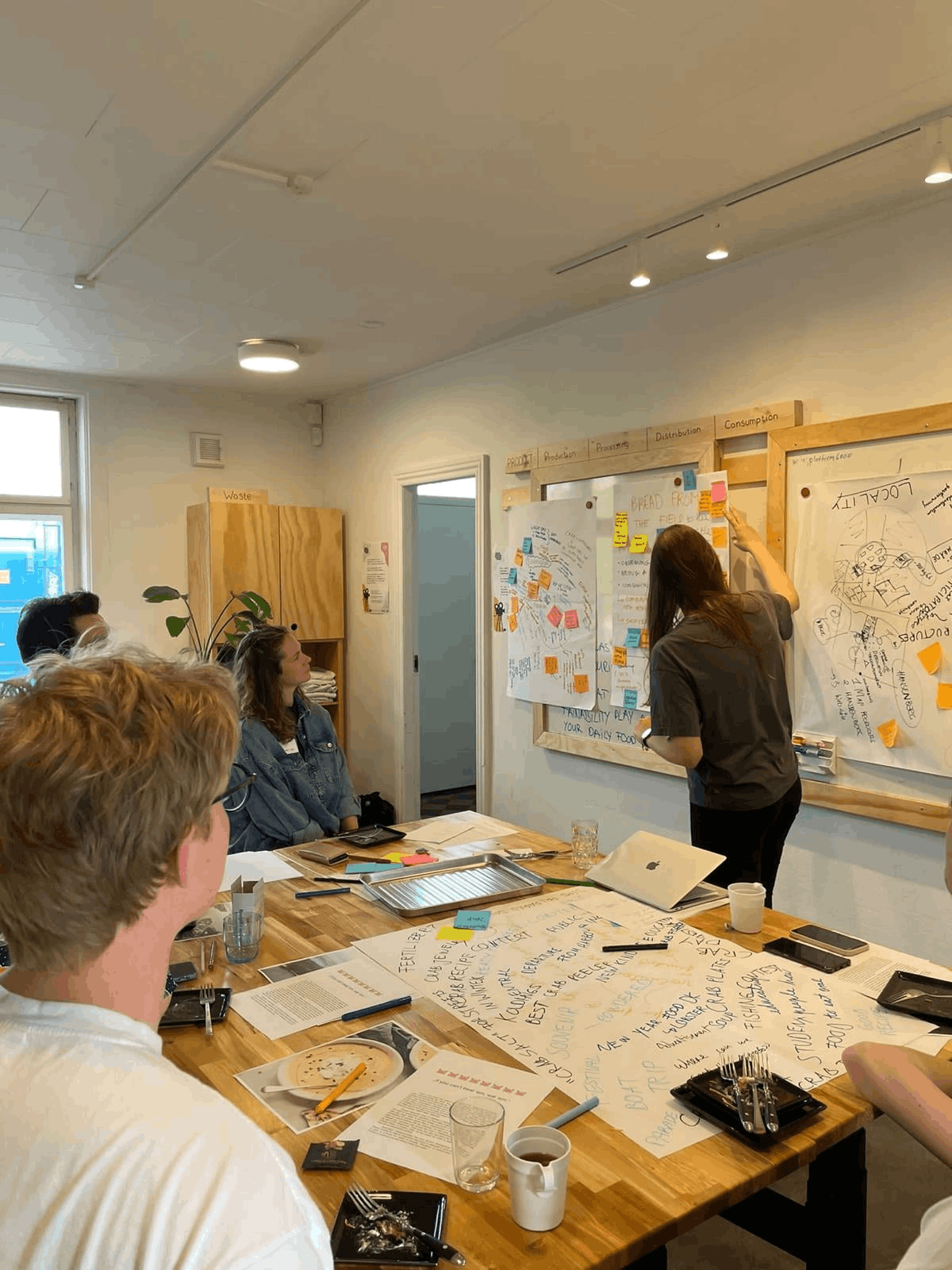 A photo of a workshop in action. People are sitting around tables, working on a project together.